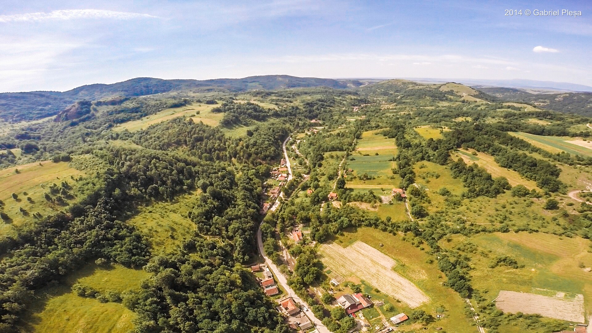 Panoramă aeriană a satului Păiușeni cu munții Zarandului în fundal